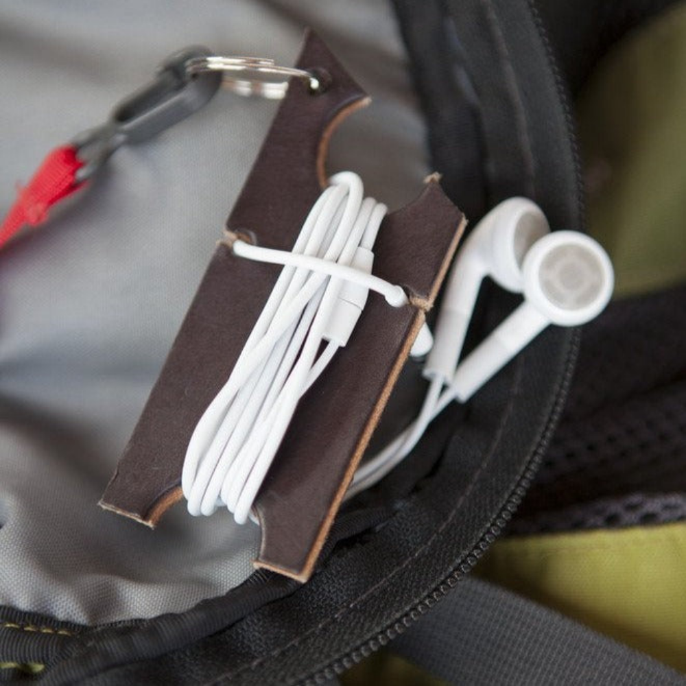 Dark brown leather keychain holder attached to the interior of a backpack with strap